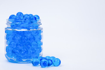 Blue orbeez in a glass jar on a light background. Selective focus.