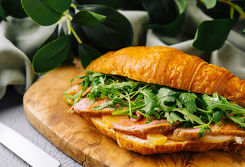 Gourmet croissant sandwich with bacon and arugula