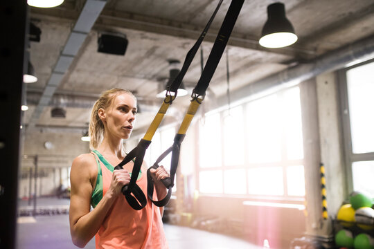 Beautiful sport woman doing suspension training, total resistance exercise. Routine workout for woman's physical and mental health.