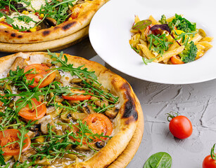 Gourmet vegetable pizzas and pasta on table
