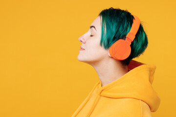 Close up side view young fun happy woman with dyed green hair wearing hoody casual clothes listen...