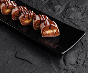 Chocolate drizzled profiteroles on dark plate