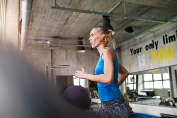 Beautiful sport woman in gym, running on treadmill. Routine workout for woman's physical and mental...
