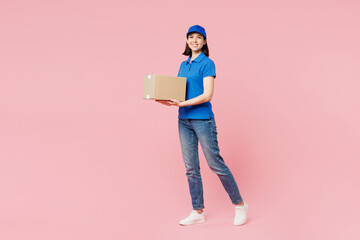 Full body side view delivery girl employee woman wearing blue cap t-shirt uniform workwear work as...