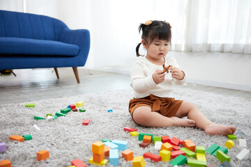 child girl playing with colorful toy blocks on the carpet floor