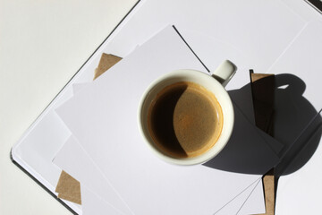Business Coffee Break. Cup of Black Coffee on Workplace with Notebook, Envelopes and Blank Cards.