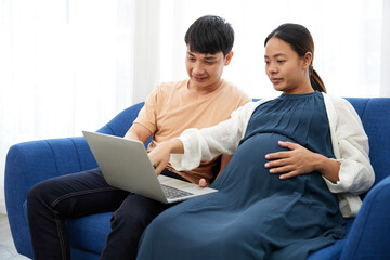 pregnant woman with her husband doing online shopping from laptop computer at home