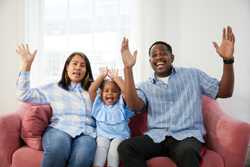 portrait excited family and raised hands celebrating success achievement pose on sofa