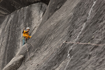 Obraz premium A man in a yellow jacket is climbing a rock wall