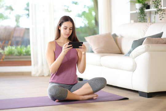 Yogi watching yoga tutorial on phone at home