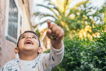 Excited autistic child pointing upwards outdoors. Joyful young boy pointing up with a look of...