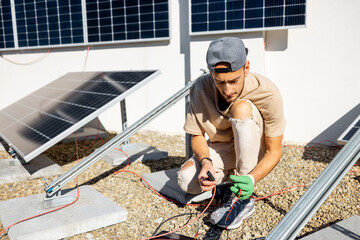 Electrician or technician checks the functionality of a solar station on the roof of a private house. Man installing solar panels on a rooftop of his house