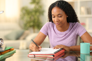 Black student taking notes learning at home