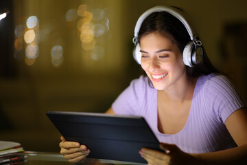 Happy woman using tablet to watch videos in the night
