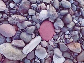 Small red stone and sea pebbles as frame on beach. Multicolor pebbles as natural abstract texture background with space for text. Close up colorful Pebbles on coast. Filled full frame. Your text. View