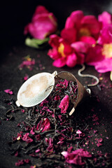Black rose tea flavored with rose petals in a steel tea infuser, focus on the center, close-up view
