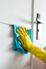 close up female hand cleaning door handle with gloves and napkin during a coronavirus pandemic