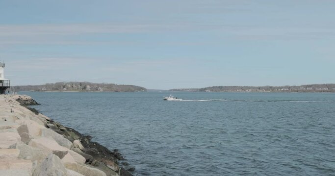 Boat travelling across the choppy waters of the Atlantic ocean past the spring point ledge light house