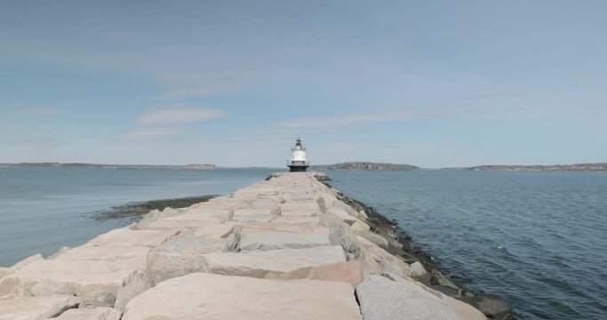Spring Point light house off in the distance at the end of a rocky peer in Portland Main in 4k.