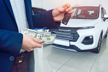 business man gives dollar cash when buying a car at showroom. Concept of purchase or rent vechicle
