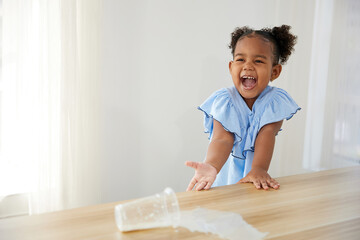 little African girl spilling milk on the table