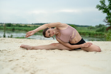 sports girl doing yoga or streching on the lake sand beach, summer time