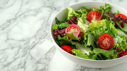 A bowl of salad with lettuce, tomatoes, and other greens. The bowl is white and placed on a marble countertop