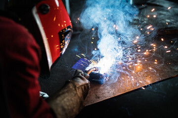 Beautiful blonde woman works as a welder in workshop, operating welding machine, wearing protective...