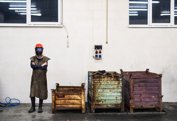 Beautiful blonde woman works as a welder in workshop, operating welding machine, wearing protective...