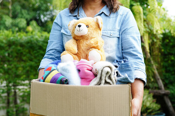 Volunteer collect cloth and doll in cardboard box to donate.
