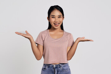 Young friendly smiling happy Asian woman wearing casual clothes with spread hands says you are welcome isolated on white background. People lifestyle concept