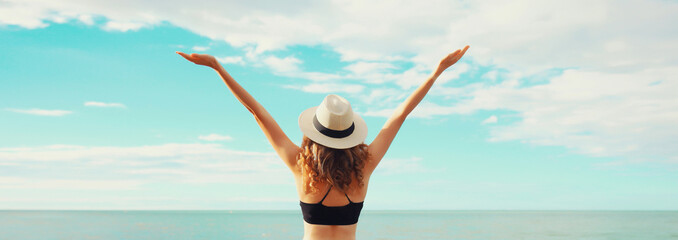Summer vacation, beautiful happy woman in bikini swimsuit raising her hands up on the beach at sea