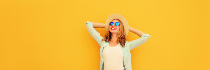 Happy relaxed young woman enjoying sunny warm day wearing summer straw hat on yellow background