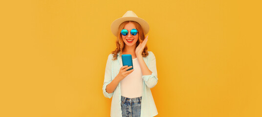 Summer portrait happy surprised young woman with mobile phone looking at device on yellow background