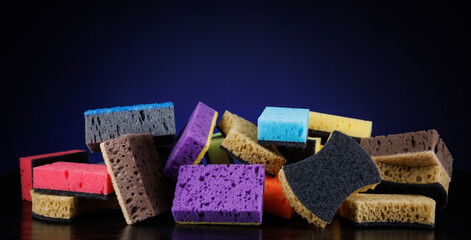 Background of mixed colorful sponges for washing dishes. Household cleaning sponge on a blue background.