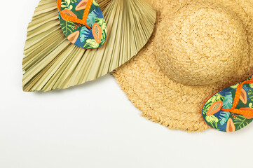 Top view of straw hat, dried palm leaf and slippers on white background. Summer fashion, vacation...