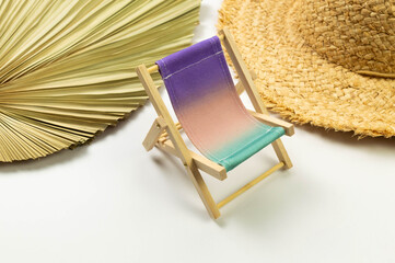 Colorful beach chair, straw hat, dried palm leaf on white background. Summer, holidays and beach...