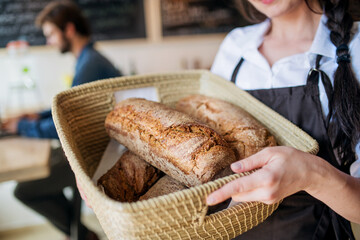 Homemade bread in small bakery. Woman holding basket with various bread freshly baked. Close up