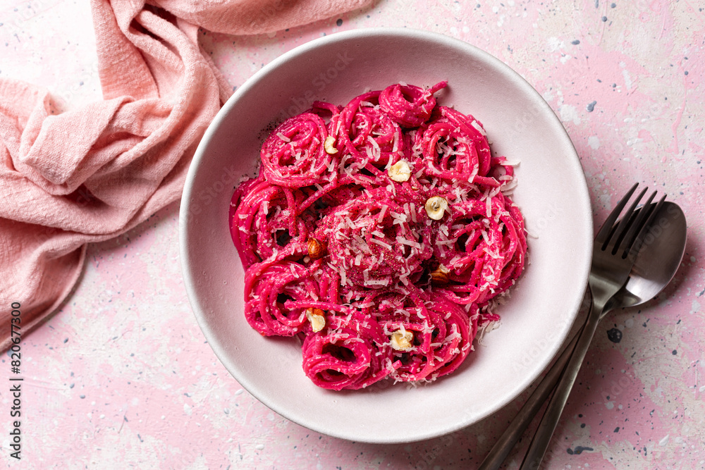 Sticker Top view of Creamy Beet Pasta spaghetti with hard cheese, nuts and black pepper. Pink background, vertical image.