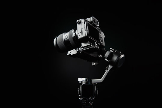 Camera mounted on gimbal on dark background. Camera stabilization technology. Electronic steadicam. Video shooting equipment