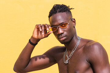 Portrait of a young happy smiling african man in sunglasses. High fashion male shirtless posing on...
