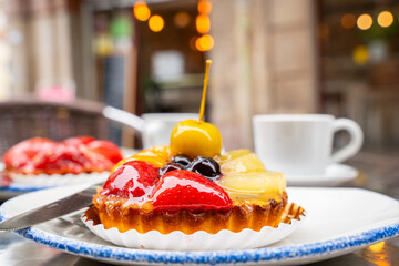 Fruit tart with cup of coffee on table in cafe. Mix fruit tart on dish and hot coffee served  in a cafe, famous refreshment and sweet for meeting place. 