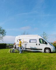 Two people relax inside a camper van parked on a grassy field in Texel, Netherlands, surrounded by...