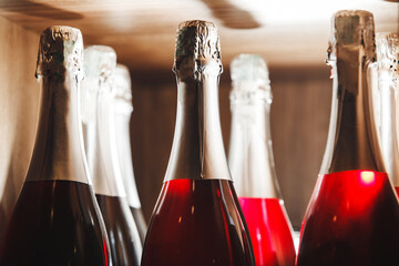 Close-Up of Sparkling Rose Wine Bottles on Wooden Shelf in Ambient Light