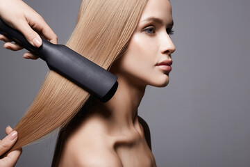 beautiful blond hair woman. Care and straightening hair with an iron