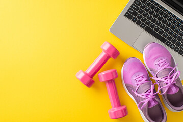 Top view of fitness equipment including pink dumbbells and sneakers next to a laptop on a bright yellow background