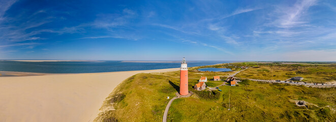 Majestic lighthouse towering over sandy beach with waves gently crashing on the shore, providing...