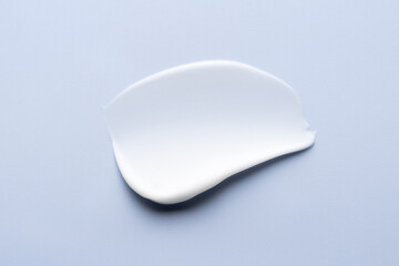 Cream texture. Cosmetic lotion smear on blue background. White creamy skincare product swatch