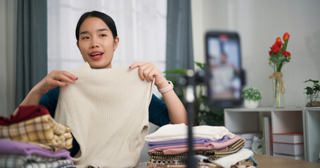 Portrait of Young asian woman business owner selling clothes live streaming on mobile phone show...