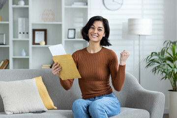 Excited woman holding envelope and celebrating good news at home